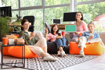 Team of female programmers having lunch on beanbags in office