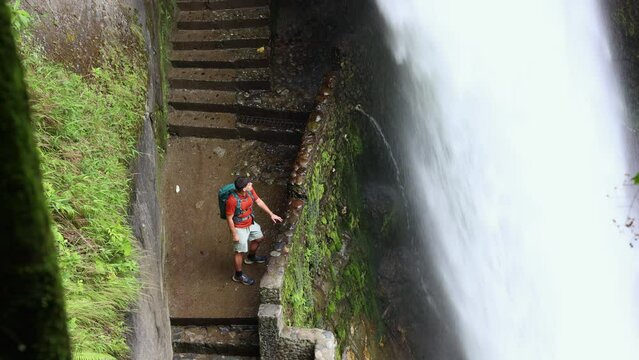 Latin Traveler with Backpack Observing Pailon del Diablo Waterfall's Force Up Close, Ecuador