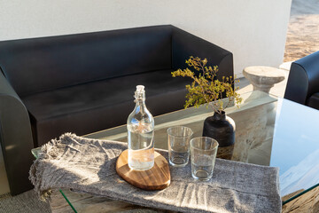 Obraz premium Modern outdoor table, glass water bottle, drinking glasses, and vase