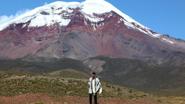 latin man in poncho posing in front of Chimborazo volcano (6,263 m), Ecuador