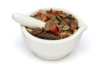 Close-up of Dry Organic warming spices or whole Garam Masala, in white ceramic mortar and pestle, isolated on a white background.