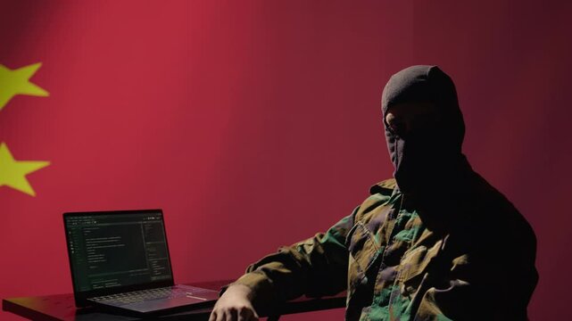 China secret police agent using mass propaganda tools on laptop to influence population minds, engaging in psychological operations. Chinese spy committing PsyOp warfare using notebook, camera B