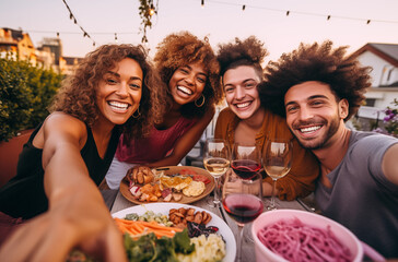 A group of friends smiling and enjoying a dinner together outdoors, with wine and delicious food on the table