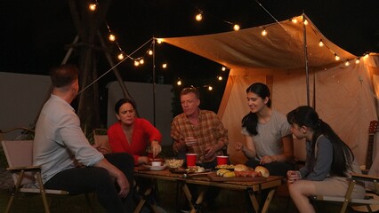 Family gather for holiday celebration in garden. Family member gather have dinner. Outdoor camping...