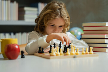 Child playing chess. Clever kid thinking about chess. Logic game for kids and logical thinking.