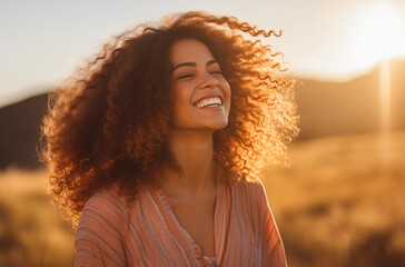 Joyful woman with curly hair enjoying sunset in a field