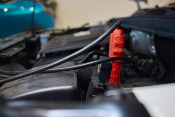 Closeup photo of black car battery connected with jumper cables for repair or recharging