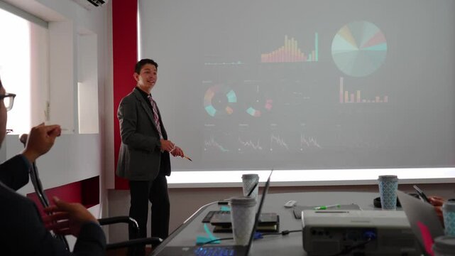 young businessman making a presentation using a projector, working team brainstorming and looking at graphics on a screen, young leader boss and teamwork discussing and analyzing data on a projection