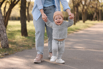Fototapeta premium Mother teaching her baby how to walk outdoors, closeup