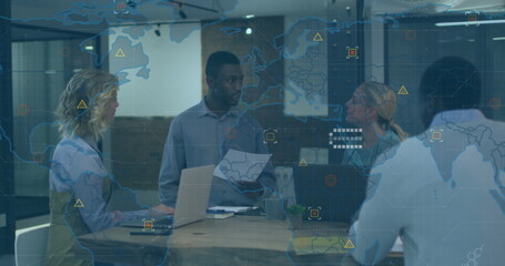 Image of world map over african american man discussing with diverse colleagues at office