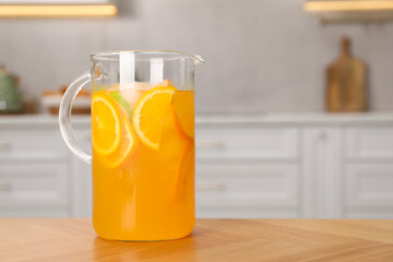 Freshly made lemonade in jug on wooden table in kitchen, space for text