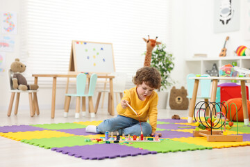 Cute little boy playing with math game Fishing for Numbers on puzzle mat in kindergarten
