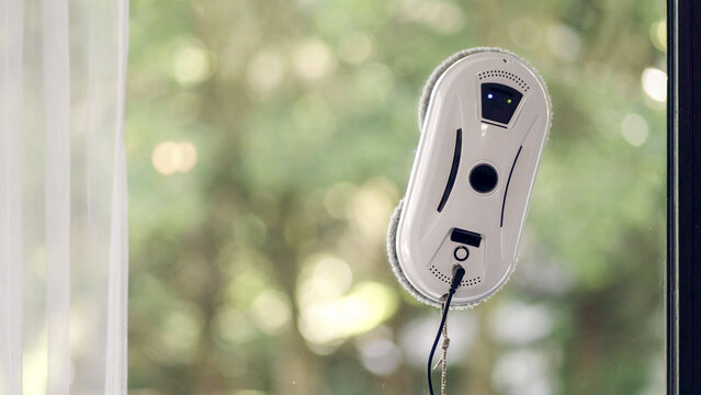 Side view of window cleaning robot on glass with light shadows.