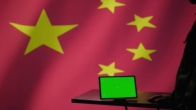 Chinese intelligence agency operator using green screen tablet to do mass propaganda on internet. CCP government secret agent engaging in psychological operations with mockup device, camera B