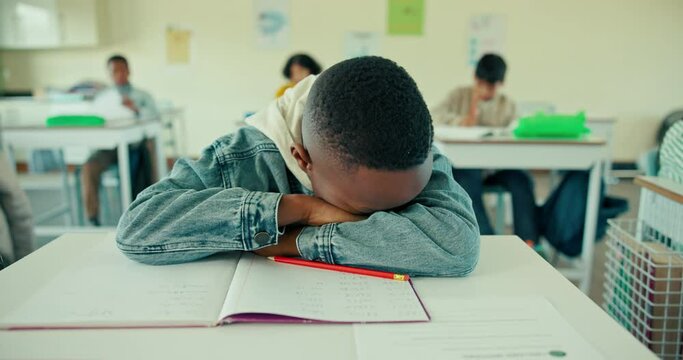 Student, desk and boy for tired in classroom, ADHD or activity with relax for sleeping learner. Education, childhood development and burnout, fatigue or male person in junior school with test