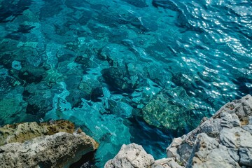 Turquoise blue ocean water gently flowing around rocks on the shore