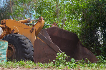 heavy construction equipment left in the forest, overgrown with plants