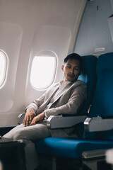 Stressed and professional Asian businessman in a business class, having a serious phone call with someone during the flight to a business meeting.