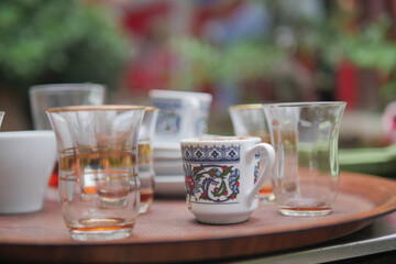 Glassware and ceramic cups on a wooden tray for serving tea and coffee up close