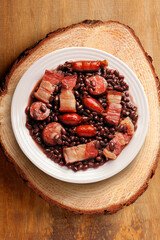 brazilian feijoada in ceramic dish isolated on rustic wooden background. Copy space