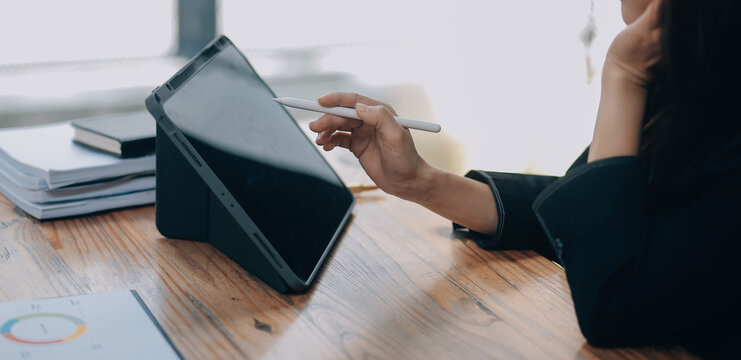 Pretty young Asian businesswoman working on laptop and taking notes In office.