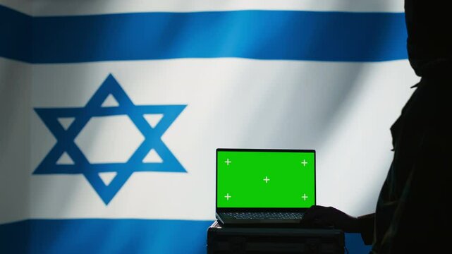Israel secret police agent uses mass propaganda tools on green screen laptop to influence population minds and spread misinformation. Mossad spy commits PsyOp sabotage using mockup notebook, camera B