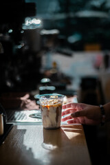 a person is holding a glass of ice cubes and a drink in front of them.