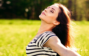 Naklejka premium Beautiful relaxing woman enjoying fresh air in sunny summer day gestering the arms flying wings with natural emotion and closed eyes. Closeup