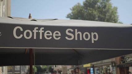 The sign of the outdoor cafe invites customers to enjoy a cup of coffee in the bright sunlight