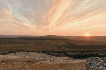 Man standing on top of hill with breathtaking view of valley at golden sunset adventure travel and nature concept