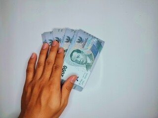 Indonesian money worth 2000 rupiah in his hand