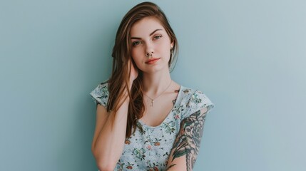 Naklejka premium Attractive Caucasian woman with intricate tattoos on her left hand and nose piercings poses against light blue background.