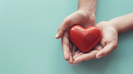 Obraz premium Hands Holding a Red Heart on a Teal Background