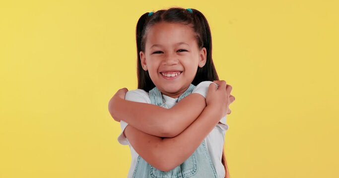 Hug, portrait and girl child for self love, smile or identity development with happiness in studio. Care, embrace and kid with positive attitude, affirmation or confident mindset on yellow background