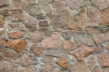 Masonry of the exterior wall made of natural rubble stone, as a background.