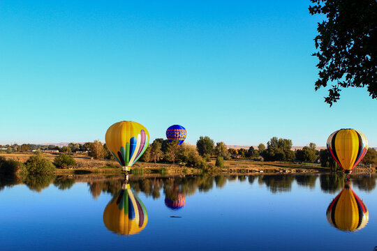 Dawn ascent of vibrant balloons over water