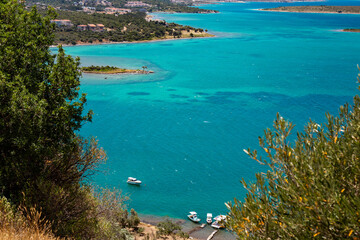 Fototapeta premium Scenic coastal view with clear cyan sea, fishing boats and islands