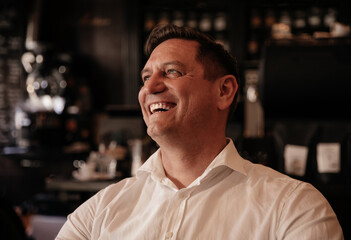 Smiling man in a white shirt enjoying a cup of coffee at a trendy cafe