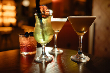 Assorted cocktails on a bar table in a dimly lit setting