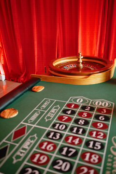 Roulette wheel and betting table with red curtains
