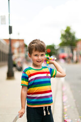 boy at pride parade holding confetti in rainbow shirt