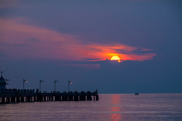 Obraz premium Fiery orange sun dips below the horizon, painting the sky and water in a breathtaking summer sunset