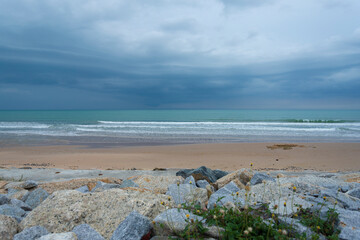 Fluffy clouds drift across a bright summer sky above a tropical beach with turquoise waves lapping at the shore