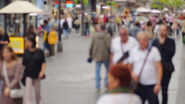 Blurred view of silhouettes of tourists and locals leisurely walk along famous Knez Mihailova street, popular pedestrian area in old town of Belgrade. Camera moves forward