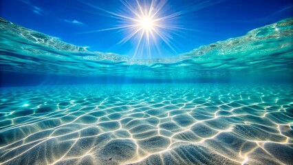 Underwater sunlit ocean. Sandy ocean floor with bright sun shining through the water's surface.
