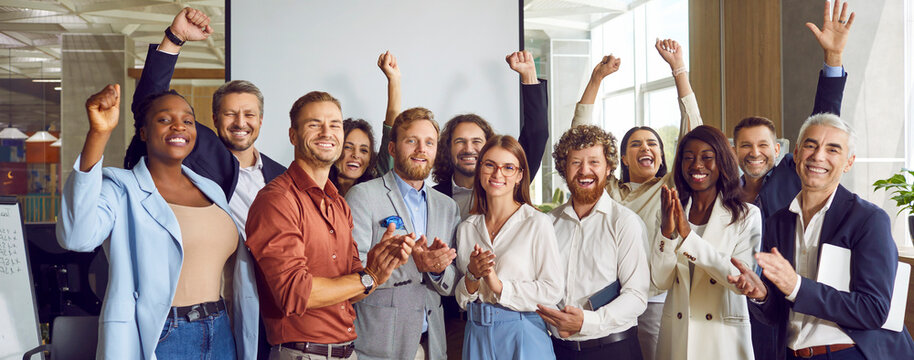 Group of multiethnic happy business people men and women looking at the camera, smiling and applauding. Company employees team or a group of staff standing in the office cheerfully. Banner.