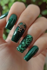 Close-up of emerald green nails adorned with glitter and gold accents.