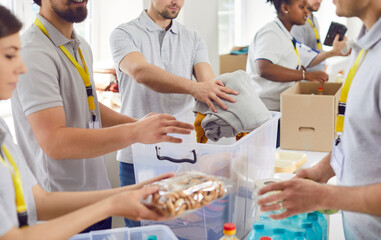 Volunteers working at humanitarian aid center. Diverse Caucasian and African American men and women collect food and clothes to take them to people in refugee shelters. Help, charity, donation concept