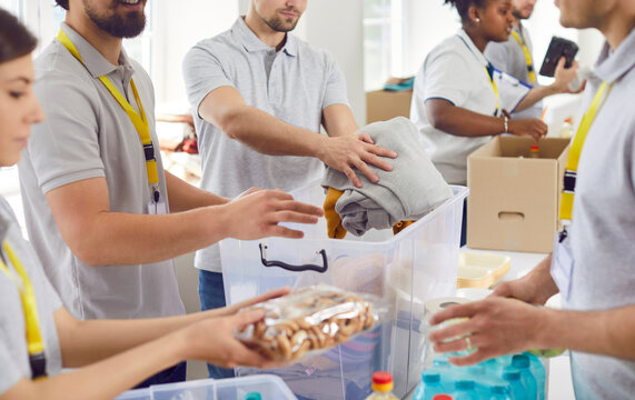 Volunteers working at humanitarian aid center. Diverse Caucasian and African American men and women collect food and clothes to take them to people in refugee shelters. Help, charity, donation concept