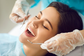 Woman patient having teeth examined by a dentist doctor using an instrument during a visit to the hospital. Dental check up showing importance of dental examinations for maintaining oral health.